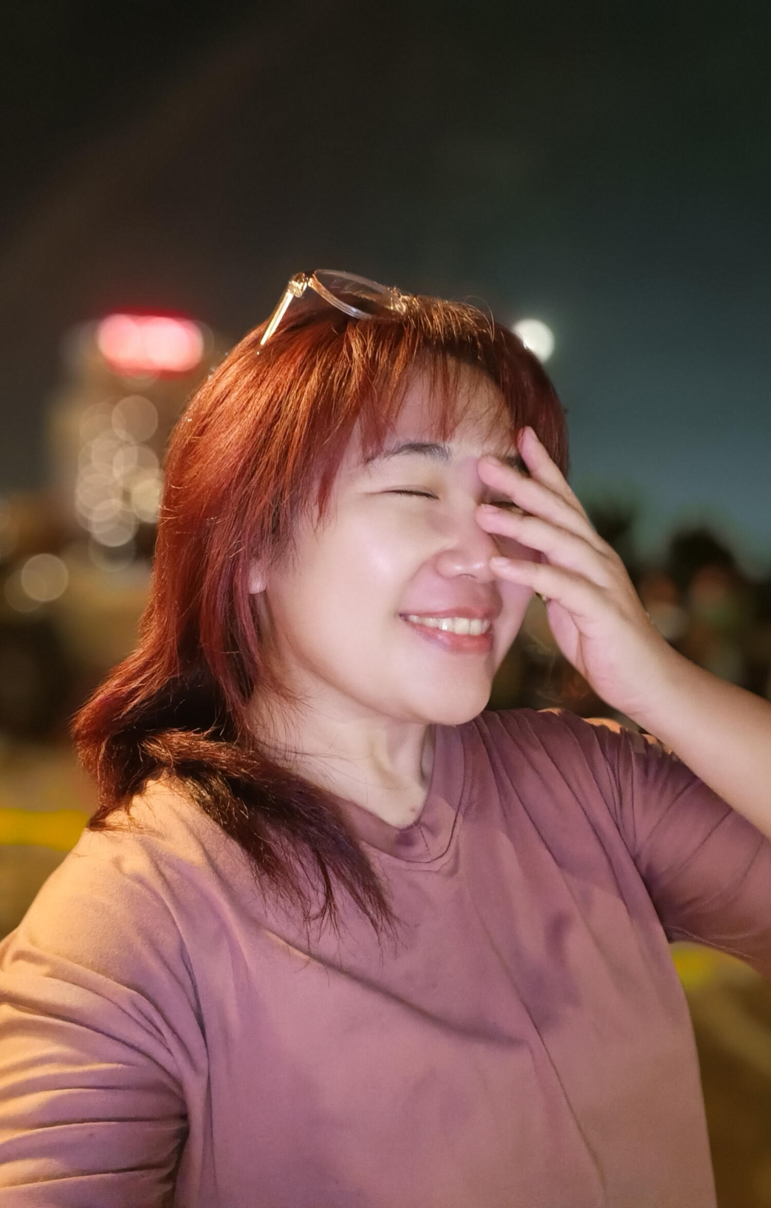 A redhead laughing with a hand covering half their face.